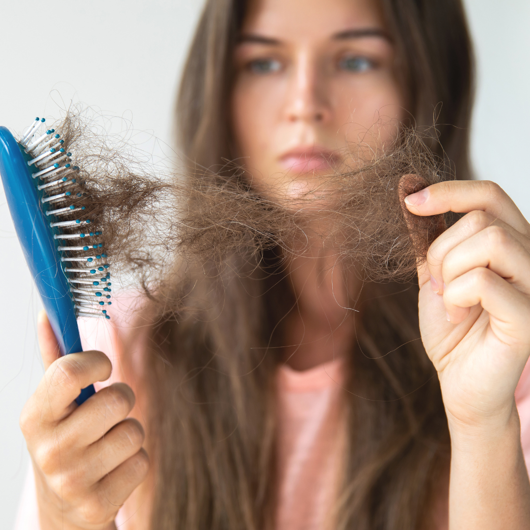 a woman pulling excess hair from hair brush