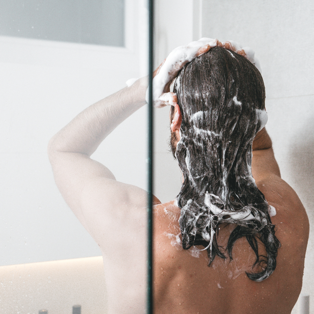 woman shampooing her hair while shower