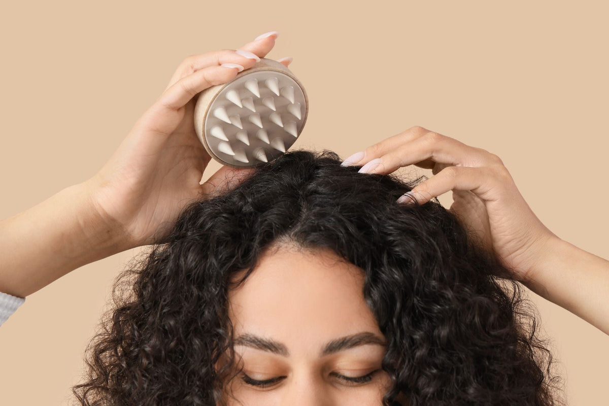 Woman using a scalp brush at the roots of her curly hair