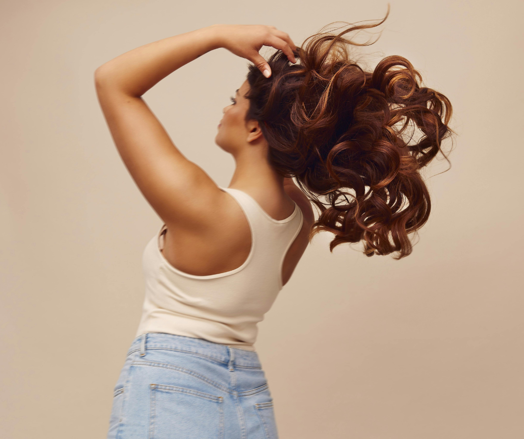 Woman with voluminous hair styled in an updo against a beige background