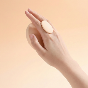 Hand holding a large beige pill against a peach background