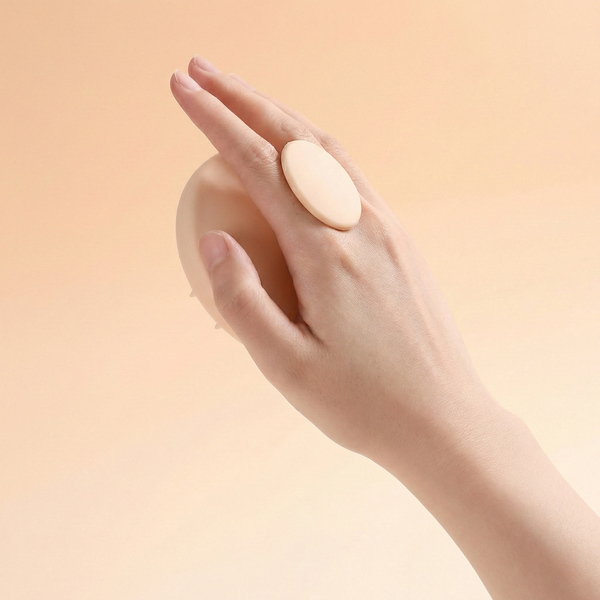 Hand holding a large beige pill against a peach background