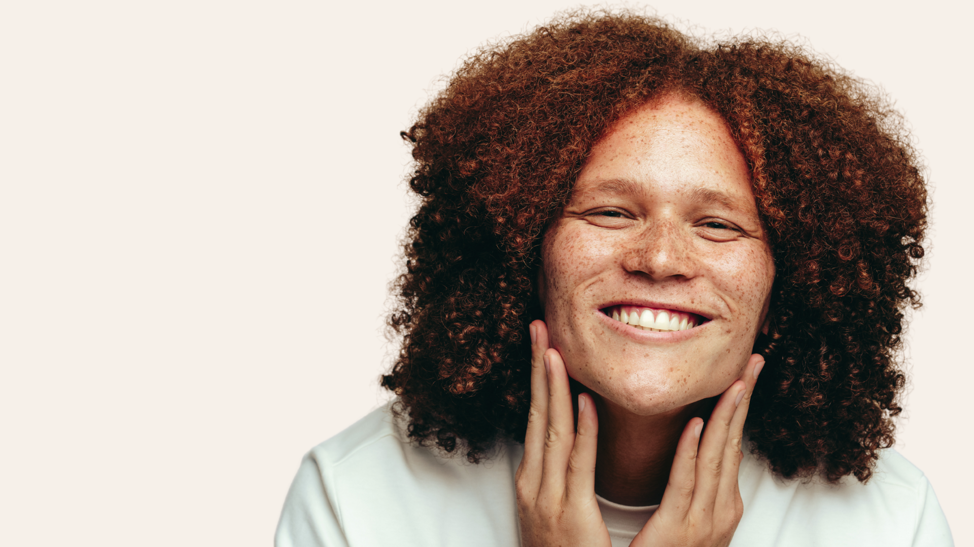 a person with very curly hair and freckles smiling